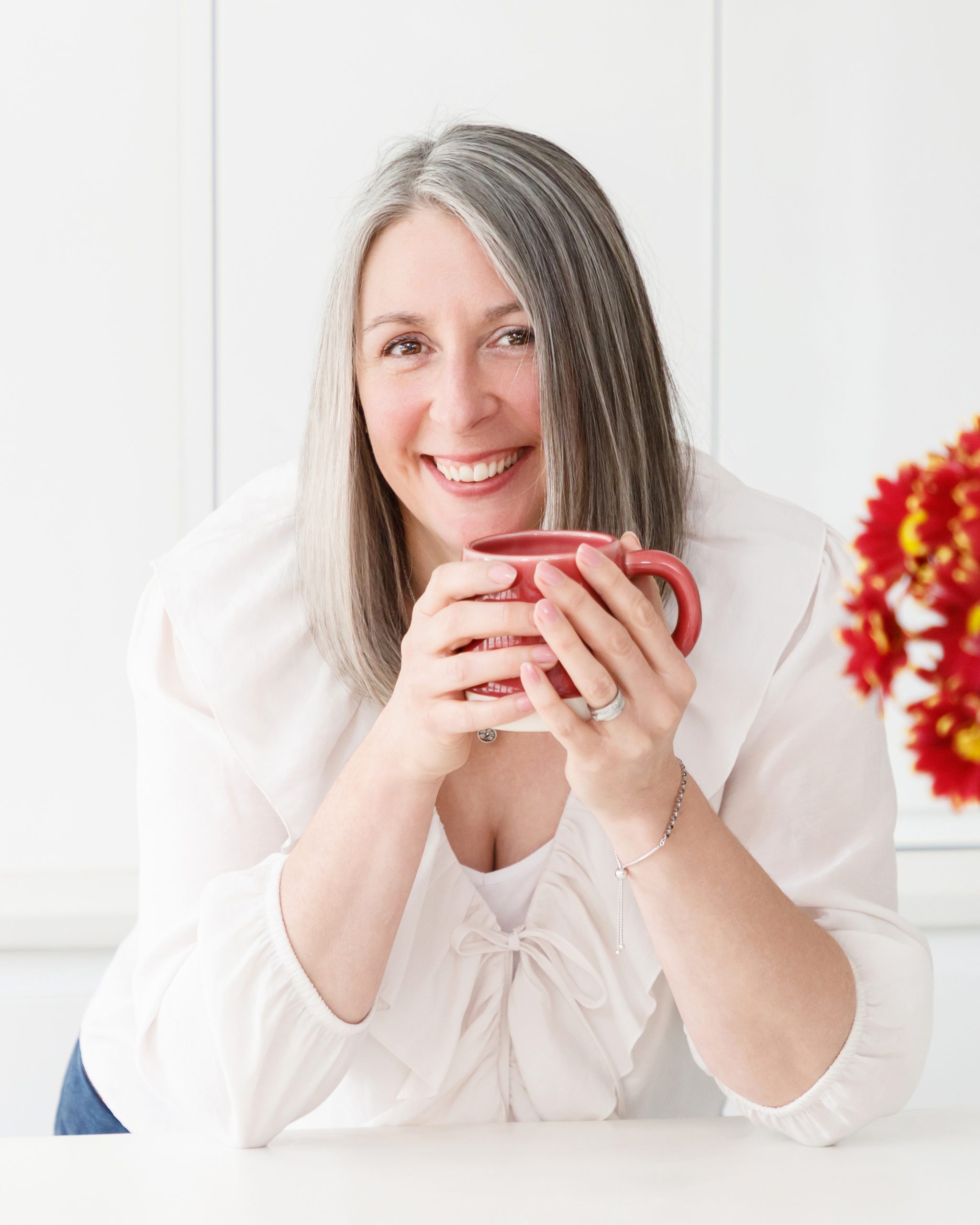 Janet Padfield, Nutritional Therapist holding a red mug and smiling into the camera